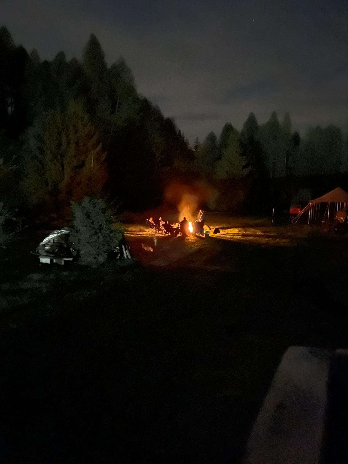 Lagerfeuer und Zelt bei Nacht auf dem Gelaende